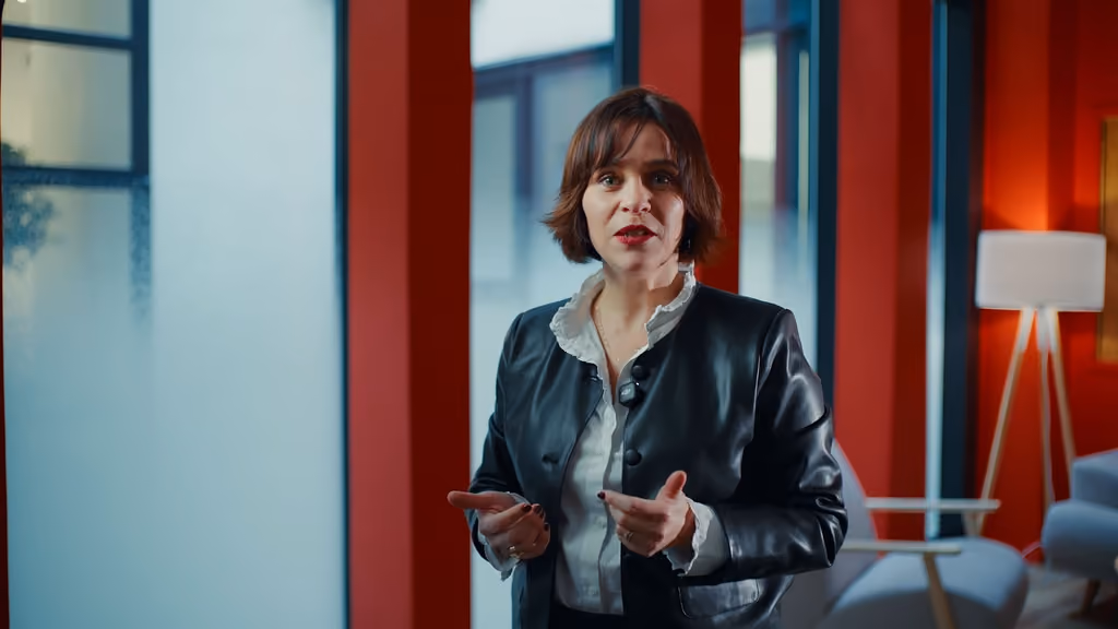 Intervenante en veste de cuir s'adressant à la caméra pour le teaser « Cap sur la performance » de Carac